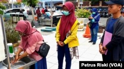 Sejumlah warga mencuci tangan di wastafel portable yang dibangun Pemkot Surabaya (Foto: VOA/ Petrus Riski).