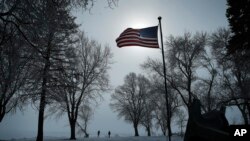 People walk along the shore of Storm Lake in Storm Lake, Iowa, Jan. 26, 2020.