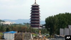 A Chinese worker climbs onto a tricycle at a construction site preparing for the upcoming APEC meeting in November to be held in the outskirts of Beijing, China, Aug. 5, 2014.