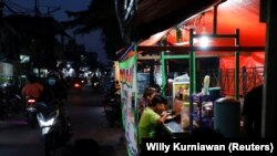 Orang-orang makan malam di tenda jajanan kaki lima saat pelonggaran PPKM di tengah pandemi COVID-19, di Jakarta, 28 Juli 2021. (Foto: REUTERS/Willy Kurniawan)