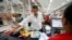 A customer puts his finger on a fingerprint scanner as part of the process to buy groceries at Bicentenario, a state-run supermarket, in Caracas, Venezuela, Sept. 25, 2014.