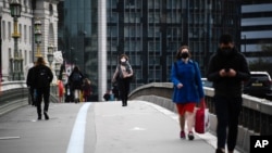 People wearing face masks walk across Westminster Bridge, in London, Britain, Oct. 7, 2020.