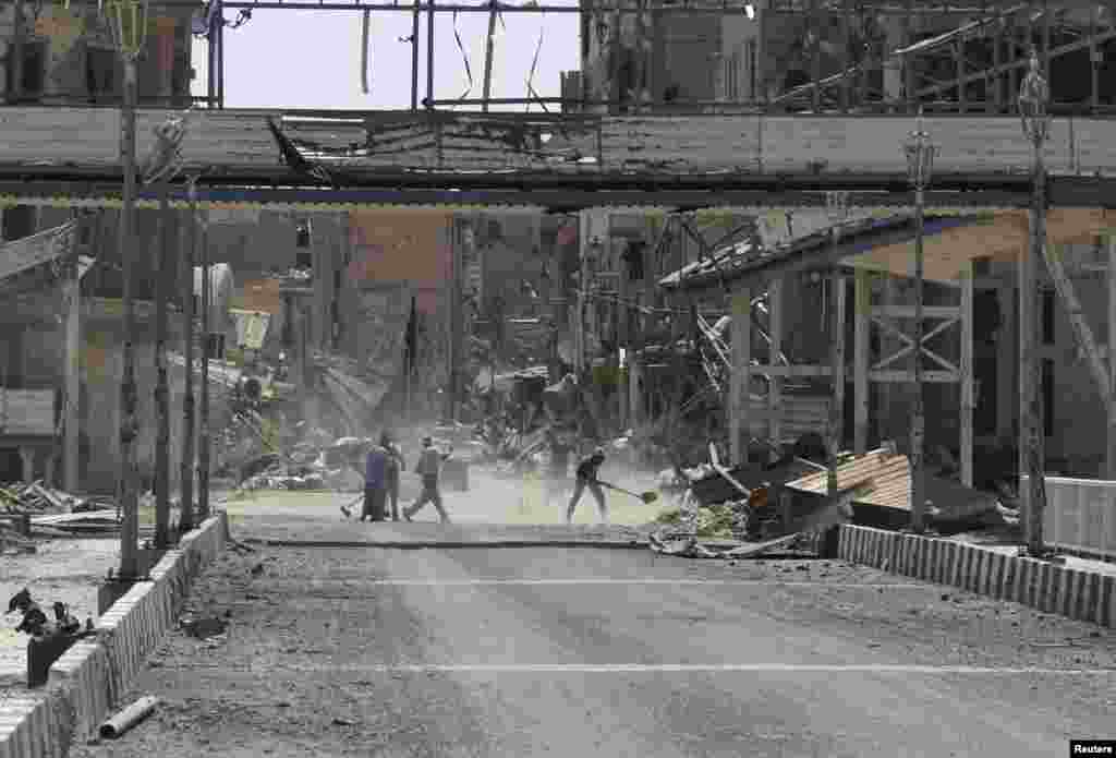 Civilians clean debris from the streets in Deir al-Zor August 20, 2013. Picture taken August 20, 2013. REUTERS/Khalil Ashawi (SYRIA - Tags: CONFLICT POLITICS CIVIL UNREST) - RTX12S4V