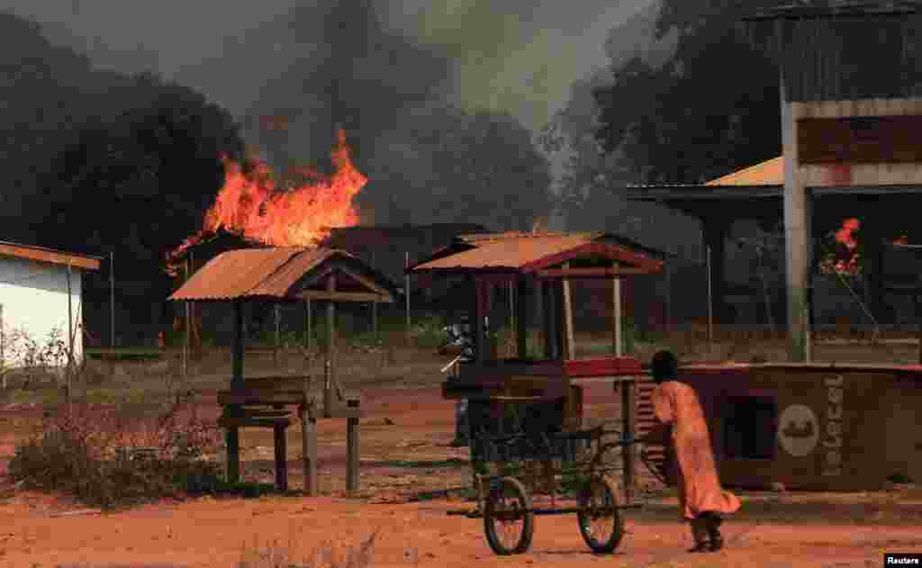 A girl pushes a hand cart past burning houses in Bossangoa, north of Bangui, Jan. 2, 2014.