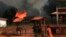 FILE - A girl pushes a hand cart past burning houses in Bossangoa, north of Bangui, Jan. 2, 2014.