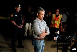 San Antonio Mayor Ron Nirenberg, center, with San Antonio Police Chief William McManus, left, brief media and others at the scene where they said dozens of people have been found dead and multiple others were taken to hospitals with heat-related illnesses after a semitrailer containing suspected migrants was found, Monday, June 27, 2022, in San Antonio. (AP Photo/Eric Gay)