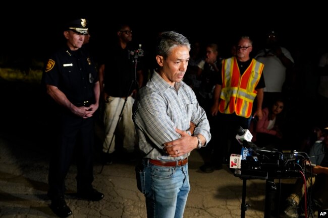 San Antonio Mayor Ron Nirenberg, center, with San Antonio Police Chief William McManus, left, brief media and others at the scene where they said dozens of people have been found dead and multiple others were taken to hospitals with heat-related illnesses after a semitrailer containing suspected migrants was found, Monday, June 27, 2022, in San Antonio. (AP Photo/Eric Gay)