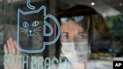 Celyta Jackson, owner of the Cat Cafe South Beach, looks out from her business during the coronavirus pandemic, July 29, 2020, in Miami Beach, Florida.