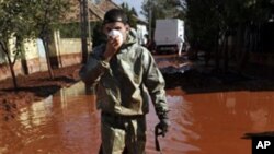 A Hungarian firefighter wearing protective gear walks through a street flooded by toxic red sludge in Devecser, Hungary, 09 Oct 2010