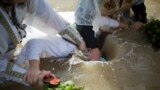 Christian Orthodox priests re-enact the baptism of Jesus, during the traditional Epiphany baptism ceremony at the Qasr-el Yahud baptism site in the Jordan river near the West Bank town of Jericho.