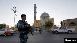 Dalam foto tertanggal 28/7/2014 ini seorang polisi Irak berjaga-jaga di depan sebuah masjid Sunni di Baghdad pada saat perayaan Idul Fitri. 