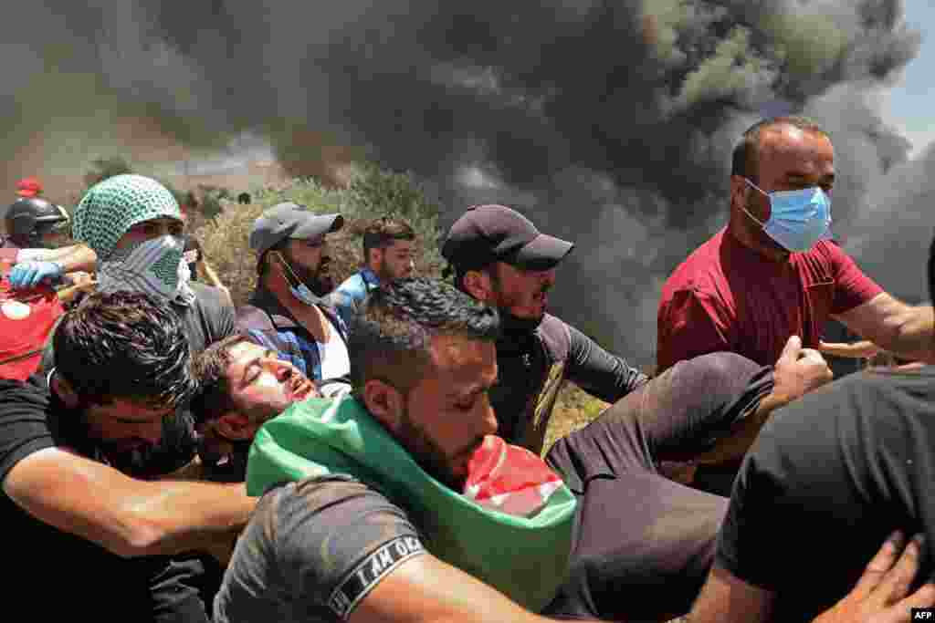 요르단강 서안 베이타 마을에서 팔레스타인 시위대가 이스라엘 군과의 충돌 중 부상당한 동료를 옮기고 있다.