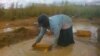 Femme extrayant les graviers de l'eau de pluie afin de nourrir sa famille et de payer les frais de scolarité des enfants, près de Lubumbashi en RDC.