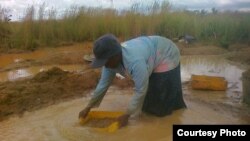 Femme extrayant les graviers de l'eau de pluie afin de nourrir sa famille et de payer les frais de scolarité des enfants, près de Lubumbashi en RDC.