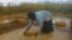 Femme extrayant les graviers de l'eau de pluie afin de nourrir sa famille et de payer les frais de scolarité des enfants, près de Lubumbashi en RDC.