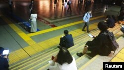 Warga Tokyo harus menunggu kereta di stasiun JR Shinagawa, karena layanan kereta sementara dihentikan saat gempa melanda Tokyo, Kamis (7/10).