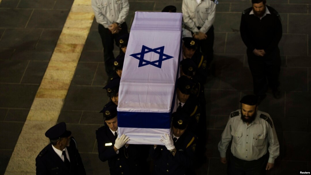 Members of the Knesset guard carry the flag-draped coffin of former Israeli prime minister Ariel Sharon outside the Knesset, Israel's parliament, in Jerusalem Jan. 12, 2014. 