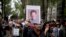FILE - A man holds up a photo of Mexican journalist Miroslava Breach, gunned down in the northern state of Chihuahua on March 23, 2017, during a march in Mexico City, March 25, 2017. 
