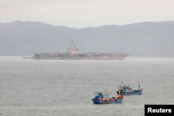 The USS Theodore Roosevelt is seen near Vietnamese fishing boats at a port in Da Nang, Vietnam, March 6, 2020.