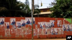 Torn election campaign posters depicting Carlos Domingos Gomes Jr. line a main road in Bissau. 