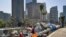 FILE - A homeless man sits at his street-side tent along Interstate 110 in downtown Los Angeles, May 10, 2018.