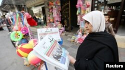 Seorang perempuan Palestina membaca koran di Khan Younis, bagian selatan Jalur Gaza (18/3). (Reuters/Ibraheem Abu Mustafa)
