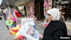 A Palestinian woman reads a local newspaper, which features the Israeli election on its front page, in Khan Younis, in the southern Gaza Strip, March 18, 2015. 