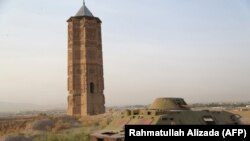 Sebuah tank Rusia yang hancur tampak di dekat satu dari dua menara masjid yang dibangun pada abad ke-12 di kota Ghazni, 16 Juli 2013 (foto: Rahmatullah Alizada/AFP)