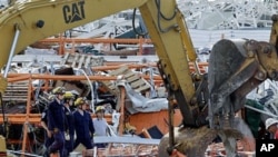 Members of Missouri Task Force One search-and-rescue team stand by as heavy equipment moves debris from a tornado-damaged Home Depot store, in Joplin , Missouri, May 24, 2011