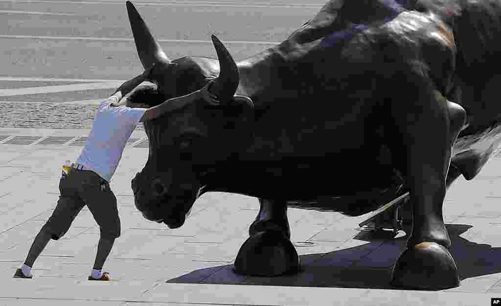 Seorang pengunjung berpura-pura berkelahi dengan patung banteng &quot;Charging Bull&quot; yang dibuat oleh seniman Italia Amerika Arturo Di Modica di Shanghai, China. 