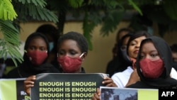 FILE - Protesters wearing face mask hold placards outside the Nigerian Police Headquarters in Abuja, Nigeria, during a rally to raise awareness about sexual violence in Nigeria, June 5, 2020.