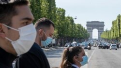 People wear face masks to help curb the spread of the coronavirus cross the Champs Elysees avenue in Paris, May 16, 2020, as France gradually lifts its Covid-19 lockdown.