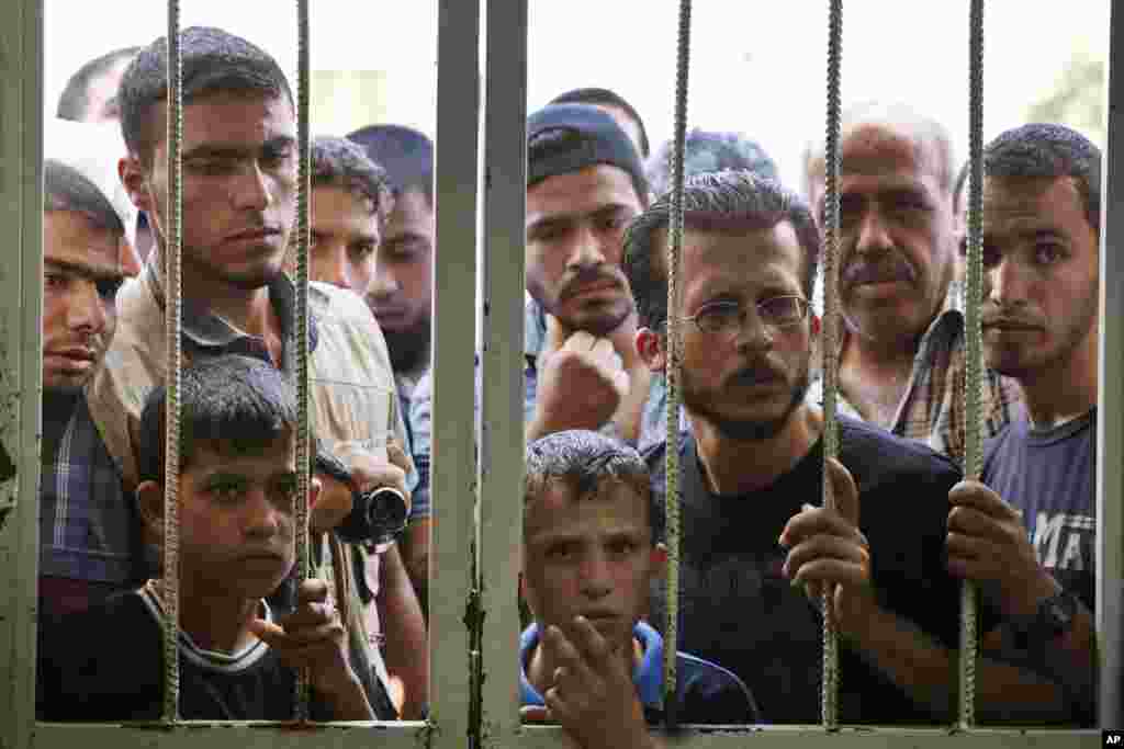 Palestinians watch as workers at the hospital morgue prepare the bodies of four members of the al-Astal family, who were killed by an Israeli airstrike, in Khan Younis, southern Gaza Strip, July 17, 2014.