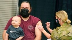 Isaac Hoffman holds his son Leo, 10 months, while receiving his Pfizer vaccine, March 25, 2021, in Spanish Fork, Utah.