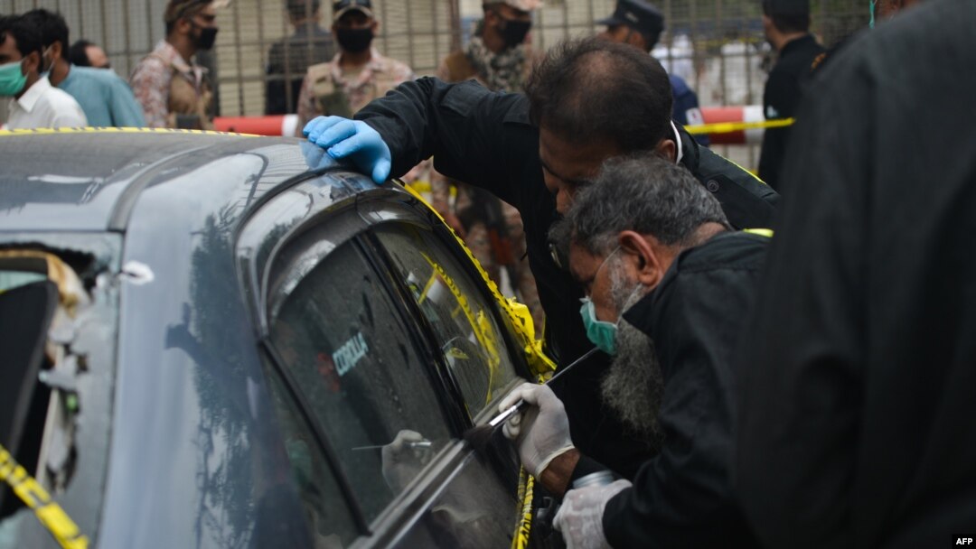 Anggota Unit TKP Polisi menyelidiki di sekitar mobil di pintu masuk utama gedung Bursa Efek Pakistan di Karachi pada 29 Juni 2020. Pasukan keamanan Pakistan menyerbu dua tempat persembunyian militan di bekas kubu pertahanan Taliban dekat Afghanistan. (Foto: AFP)