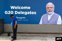 FILE - A worker cleans in front of a G20 communication billboard with a portrait of India' prime minister Narendra Modi at the G20 venue, days ahead of its commencement in New Delhi on September 7, 2023.