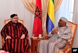 FILE — In this photo dated December 3, 2018 and provided by the Moroccan News Agency, Moroccan King Mohammed VI, left, visits Gabonese President Ali Bongo Ondimba at military Hospital in Rabat.