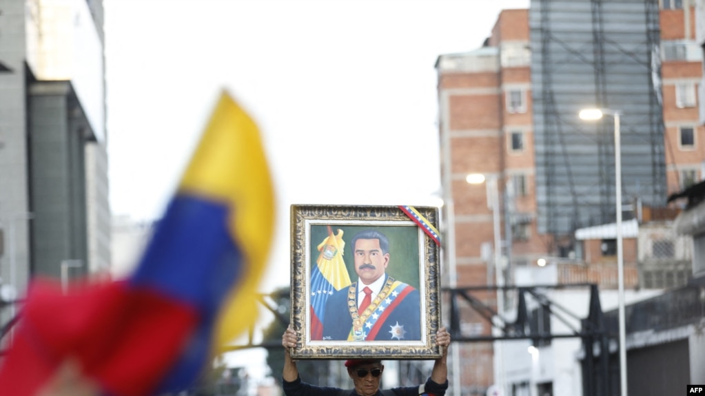 ARCHIVO - Un partidario del presidente venezolano Nicolás Maduro sostiene un retrato del mandatario durante una manifestación en respaldo de los resultados de las elecciones presidenciales en Caracas el 3 de agosto de 2024.