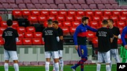 Getafe players wearing T-shirts that say "Football for the fans" in Spanish welcome into the pitch FC Barcelona players prior to their Spanish La Liga soccer match at the Camp Nou stadium in Barcelona, Spain, April 22, 2021. 