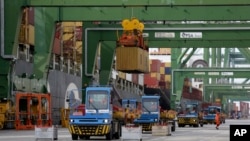 FILE - Containers are loaded and unloaded from ships at the Port of Sines, in Sines, Portugal, Feb. 12, 2020. 