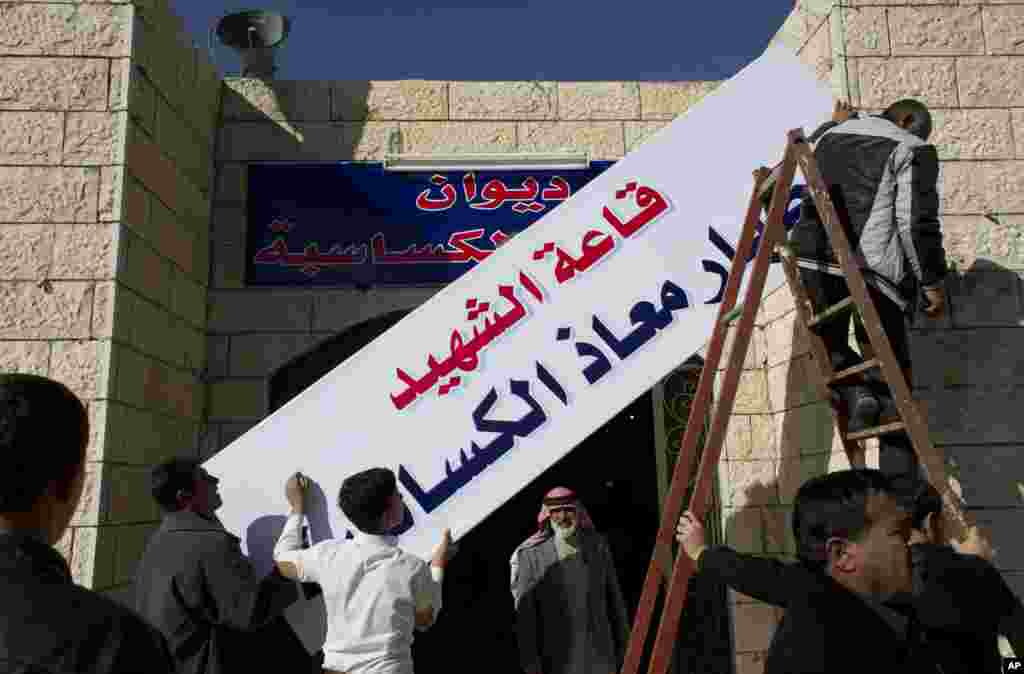Workers hang a banner in Arabic that reads, &quot;the hall of martyr pilot Muath al-Kaseasbeh,&quot; over the entrance of the tribe&#39;s gathering divan, at his home village of Ai, near Karak, Feb. 4, 2015.