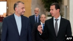 A handout picture released by the Syrian Arab News Agency shows Iranian Foreign Minister Hossein Amir Abdollahian, left, speaking with Syrian President Bashar al-Assad in the capital Damascus on Aug. 29, 2021.