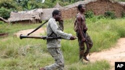 Des soldats alliés au président Alassane Ouattara traversent un terrain de camping à distance désert le long de la piste forestière menant de Bloléquin, vers la frontière entre la Côte d'Ivoire de l'ouest avec le Libéria, 1er juin 2011. 