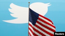 FILE - The Twitter Inc. logo is shown with the U.S. flag during the company's IPO on the floor of the New York Stock Exchange in New York, Nov. 7, 2013. 