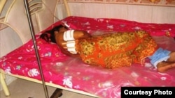 An unidentified garment worker lying on a hospital bed with multiple gunshot wounds to her back. 