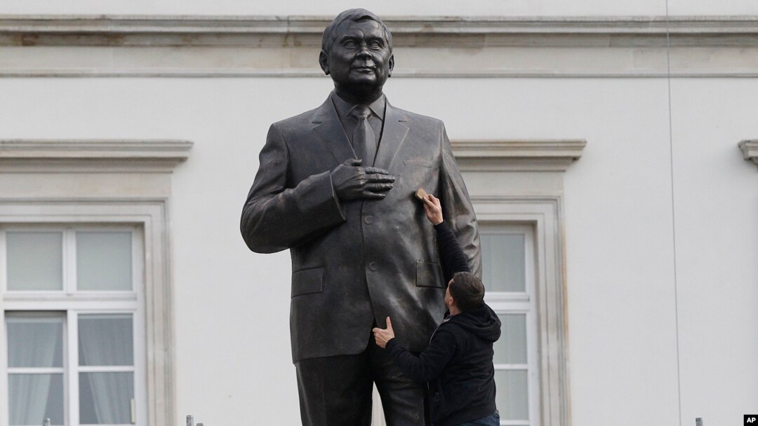 A worker cleans a statue depicting late Polish President Lech Kaczynski after it was installed at a central square in Warsaw, Poland, Nov. 7, 2018.