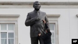 A worker cleans a statue depicting late Polish President Lech Kaczynski after it was installed at a central square in Warsaw, Poland, Nov. 7, 2018.