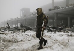 FILE - A member of the self-proclaimed Donetsk People's Republic forces walks near a building, destroyed during battles with the Ukrainian armed forces, at Donetsk airport, Jan. 12, 2016.