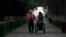 FILE - An elderly Chinese woman accompanied by her caregiver walks down a tree lined lane in Changchun in northeastern China's Jilin province, Aug. 27, 2010.