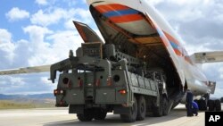 FILE - Military vehicles and equipment, parts of the S-400 air defense systems, are unloaded from a Russian transport aircraft, at Murted military airport in Ankara, Turkey, July 12, 2019. 